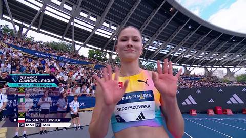 Pia Skrzyszowska, polska lekkoatletka, stoi przed publicznością na stadionie podczas mityngu Diamentowej Ligi w Paryżu. Jest ubrana w sportowy str&oacute;j i uśmiecha się do obiektywu, unosząc ręce w geście pozdrowienia.
