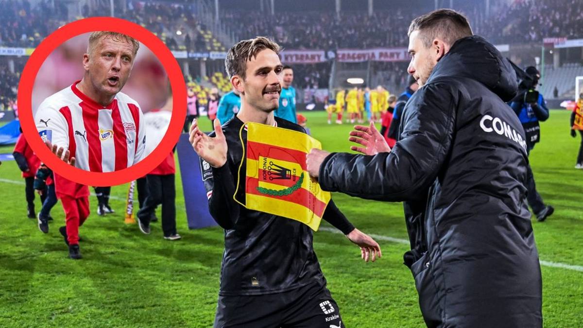 Piłkarz w czarnej koszulce trzyma flagę Cracovii, podaje rękę trenerowi w czarnej kurtce.