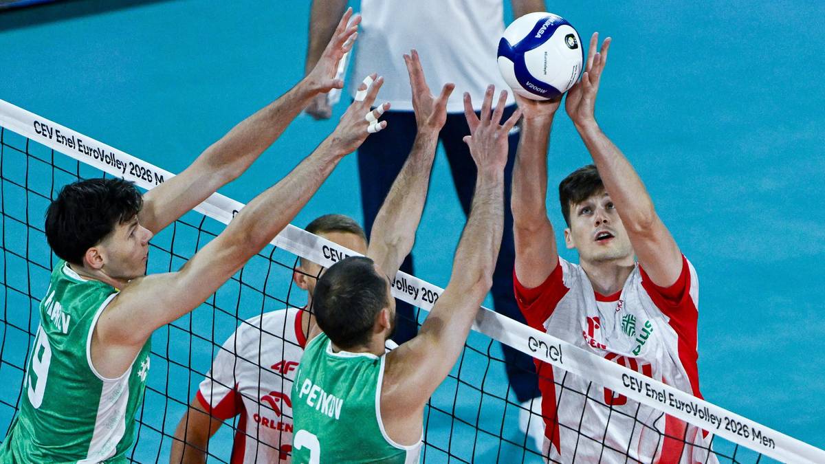 Zacięta akcja meczu siatkówki z kilkoma zawodnikami walczącymi o piłkę nad siatk
