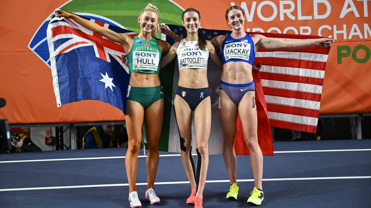 Trzy lekkoatletki pozują do zdjęcia z flagami swoich kraj&oacute;w po zawodach.