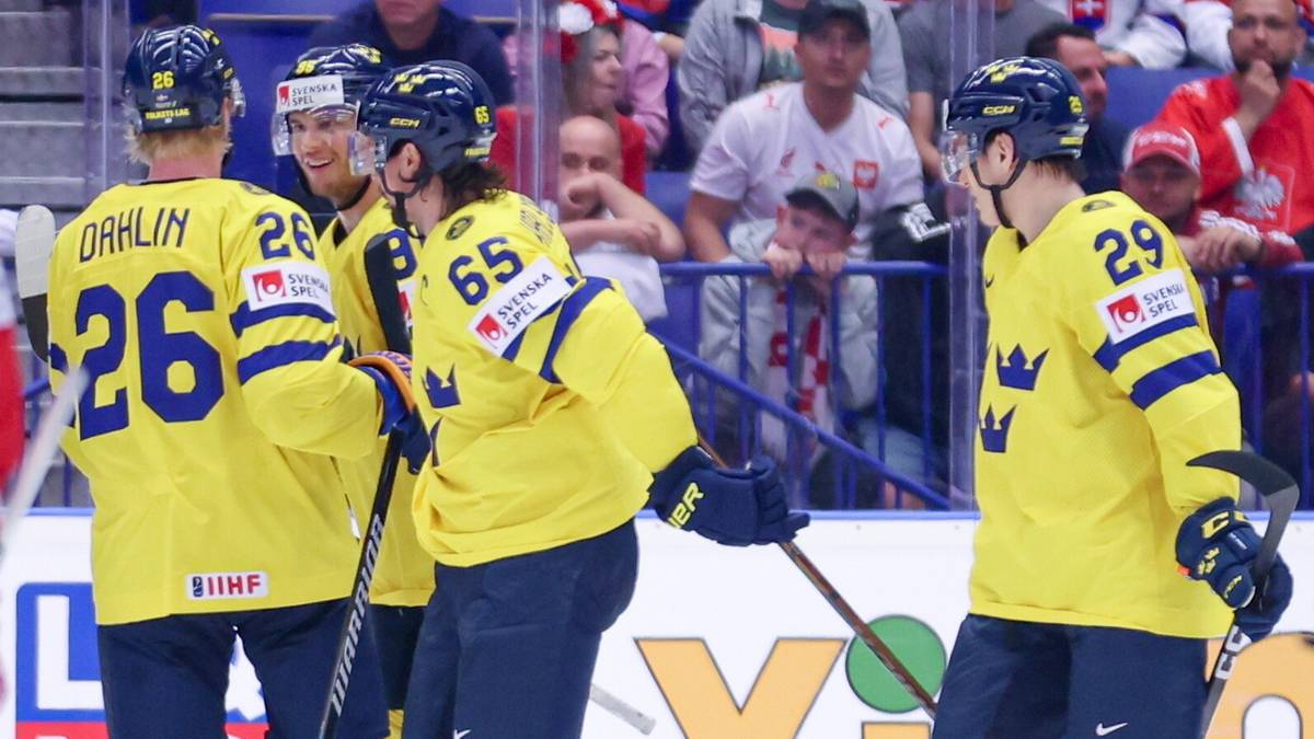 Trzech zawodników w żółtych koszulkach reprezentacji Szwecji w hokeju na lodzie, z numerami 26 i 65, odwraca się tyłem do widza, jeden zawodnik z numerem 29 stoi przodem do widza. W tle widoczni są kibice.