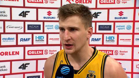 Młody mężczyzna, zawodnik koszykówki, ubrany w żółtą koszulkę, udziela wywiadu.