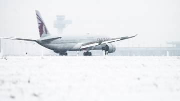 Samolot linii Qatar Airways na zaśnieżonym pasie startowym.
