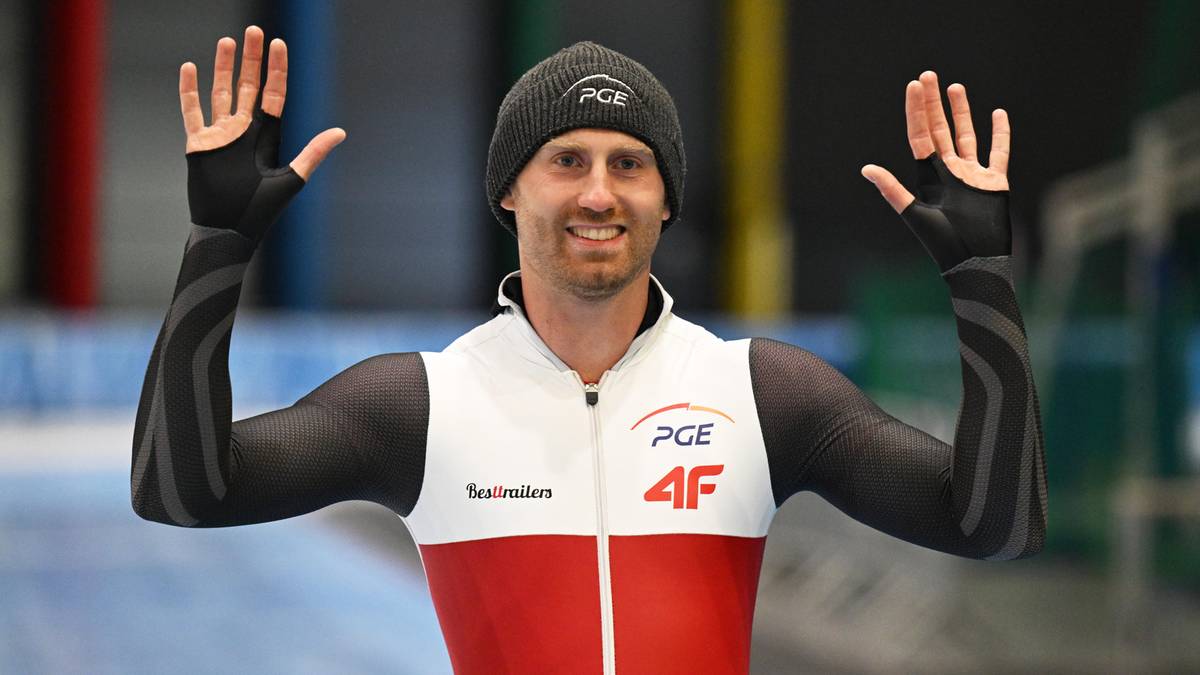 Marek Kania, polski panczenista, w stroju sportowym z podniesionymi rękami.