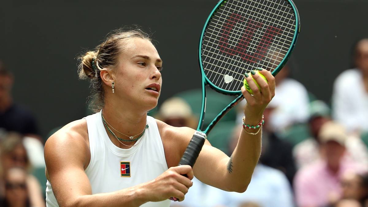 Aryna Sabalenka, zawodniczka tenisa, trzyma rakietę i piłkę tenisową podczas meczu na trawiastym korcie.