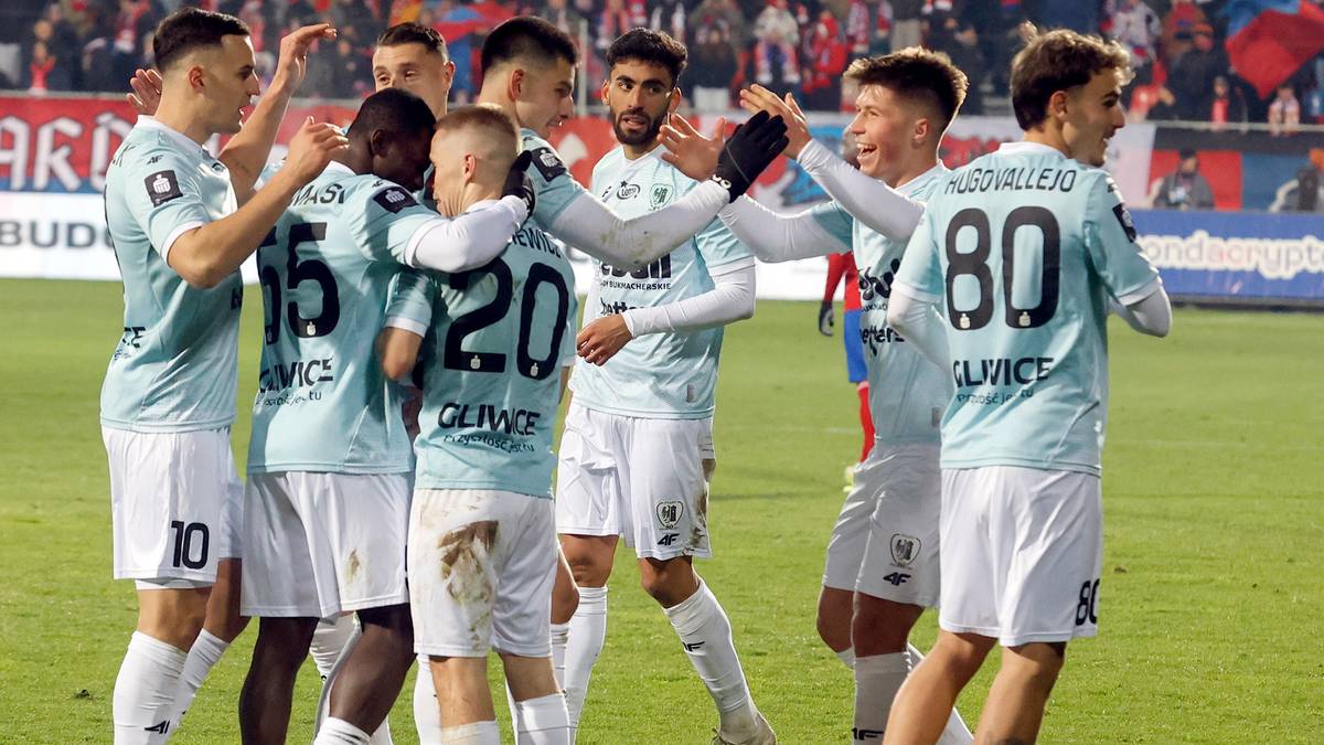 Grupa piłkarzy w jasnoniebieskich strojach świętuje na boisku piłkarskim.