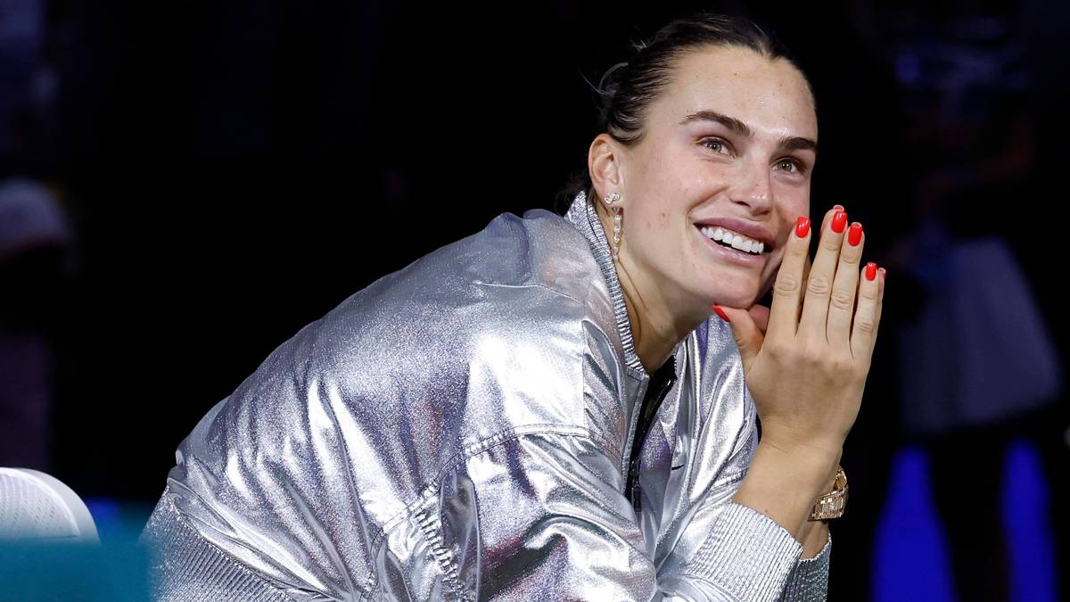 Aryna Sabalenka uśmiecha się w srebrnej kurtce.