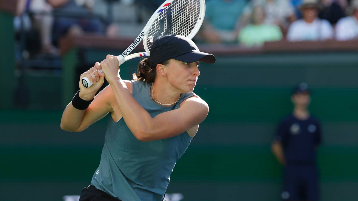 Tenisistka w czapce z daszkiem i sportowym topie przygotowuje się do uderzenia rakietą tenisową.