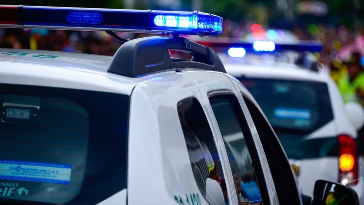 Radiow&oacute;z policyjny z włączonymi niebieskimi sygnałami świetlnymi.