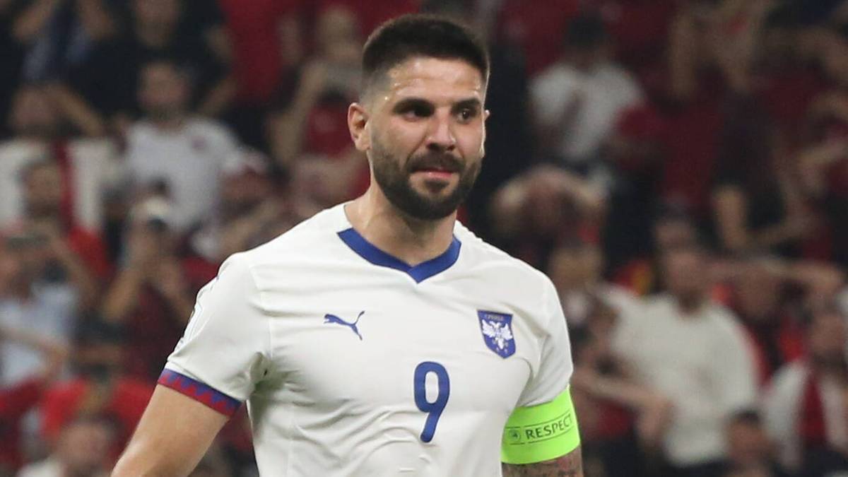 Piłkarz reprezentacji Serbii, Aleksandar Mitrović, z numerem 9 na koszulce, na tle trybun stadionu podczas meczu eliminacji Mistrzostw Świata.