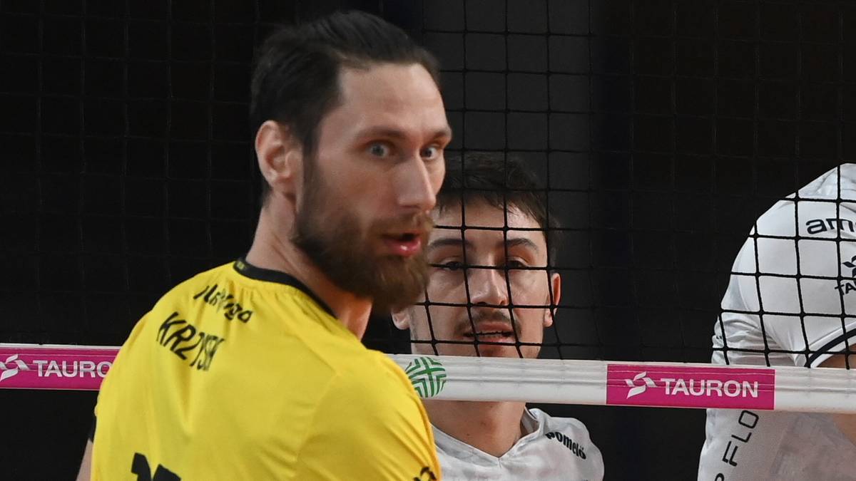 Siatkarz w żółtej koszulce z numerem 17 po lewej stronie, z prawej zawodnik w białej koszulce PGE GiEK Skra Bełchatów serwuje piłkę.