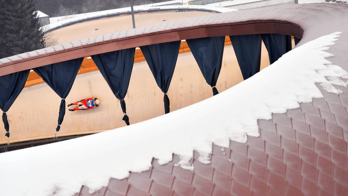 Sportowiec na sankach zjazdowych ślizga się po torze lodowym.