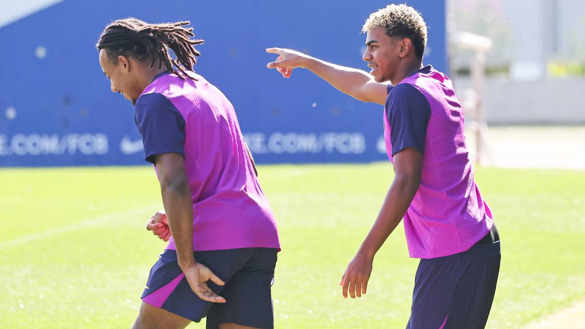 Dwóch piłkarzy FC Barcelony w strojach treningowych podczas zajęć na boisku.