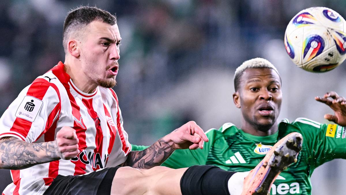 Trzej piłkarze walczący o piłkę na boisku podczas meczu piłkarskiego.