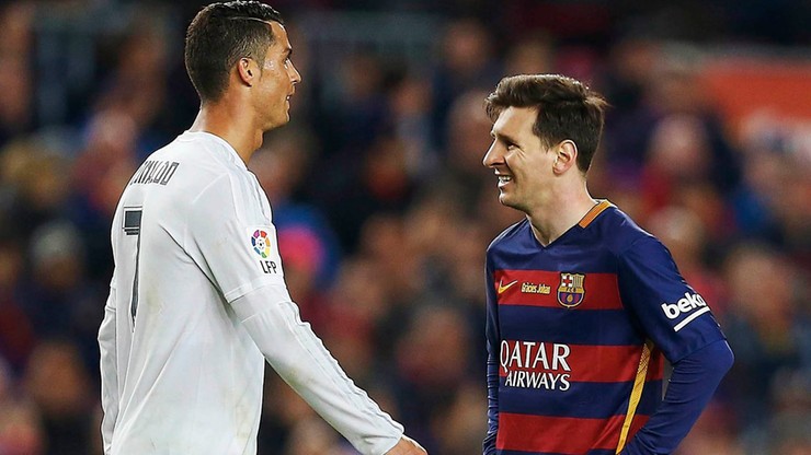 Dw&oacute;ch piłkarzy, Cristiano Ronaldo w białej koszulce i Lionel Messi w bordowo-granatowej koszulce, stoją obok siebie i rozmawiają, patrząc na siebie.