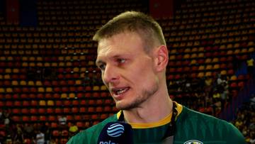 Portret mężczyzny, Jurija Gladry, z bliska, w zielonej koszulce sportowej, z mikrofonem przed ustami.