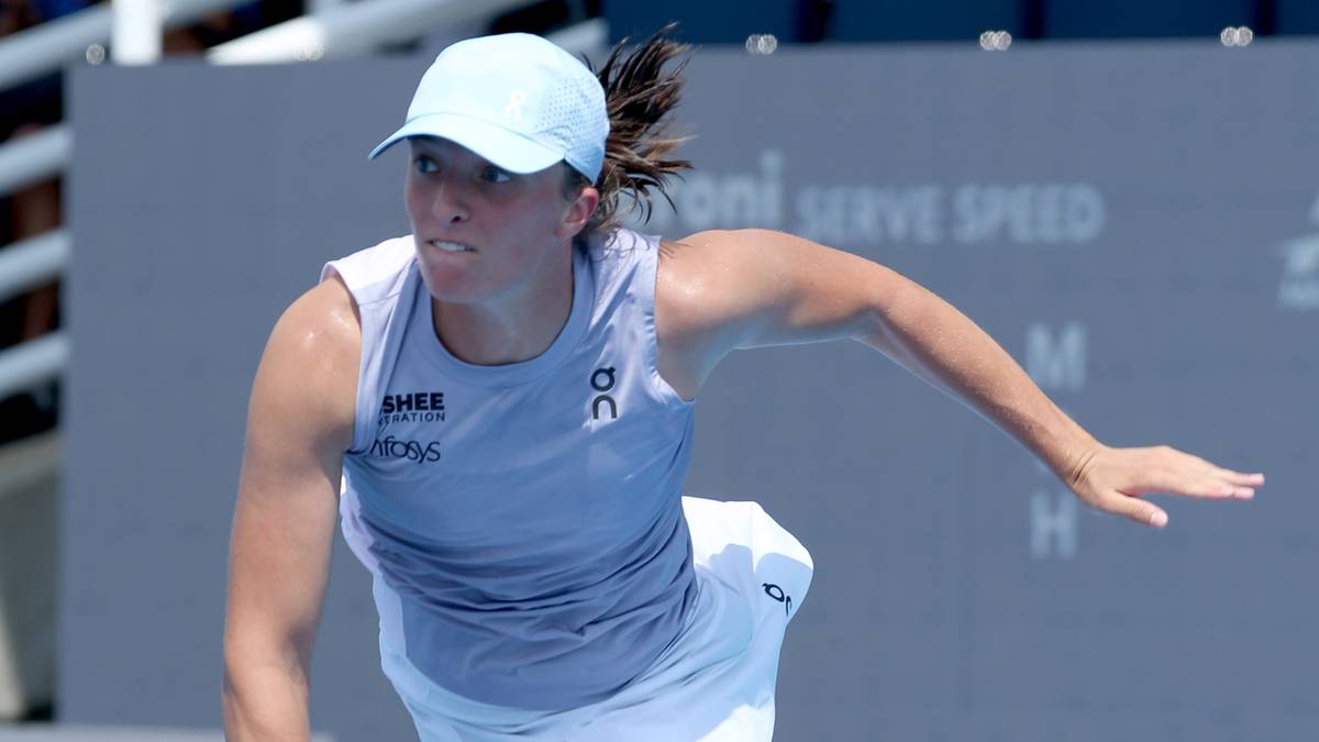 Iga Świątek podczas meczu tenisowego, w niebieskiej czapce i sportowym stroju.