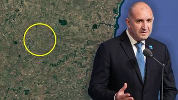 Mężczyzna w garniturze przemawia przy mikrofonie na tle satelitarnego zdjęcia terenu z zaznaczonym ż&oacute;łtym okręgiem.