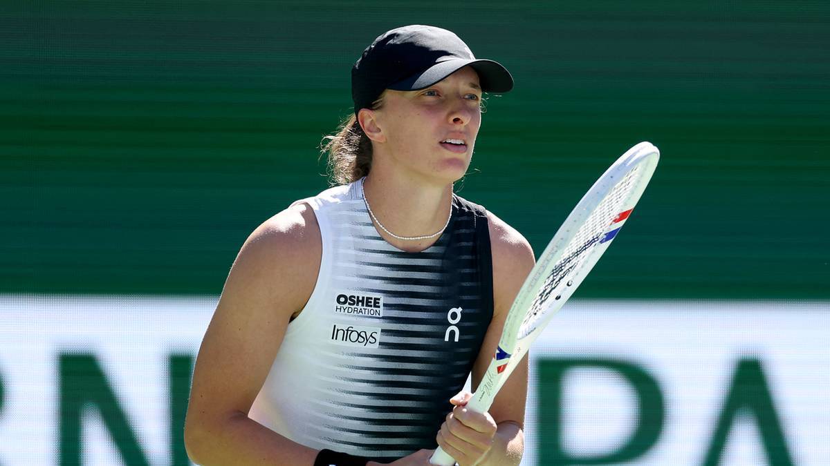 Tenisistka Iga Świątek w czapce z daszkiem i sportowym stroju, trzymająca rakietę tenisową.