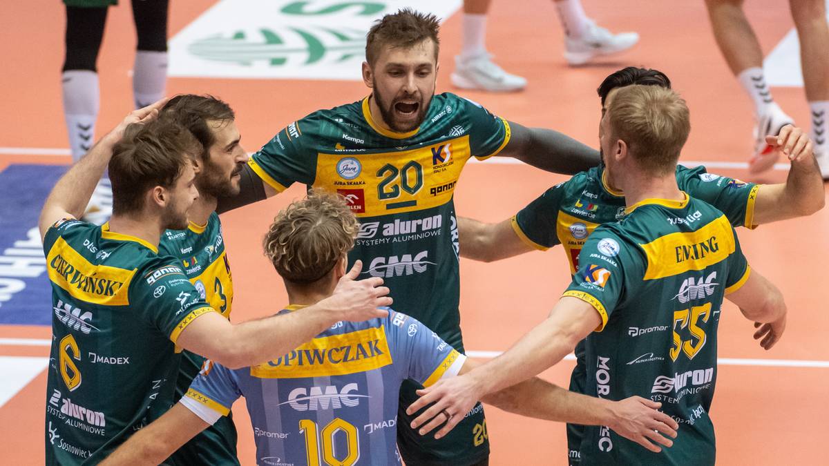 Grupa siatkarzy Aluron CMC Warta Zawiercie w zielono-ż&oacute;łtych strojach tworzy koło, obejmując się nawzajem, z widocznymi numerami na koszulkach.