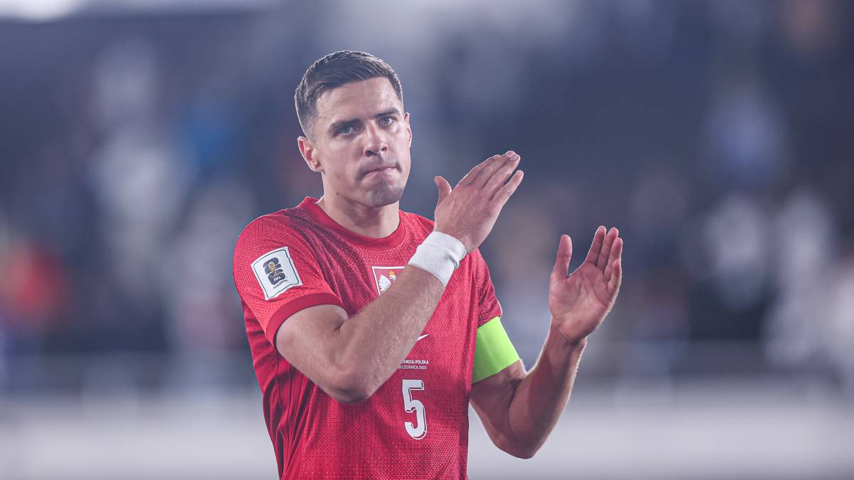 Jan Bednarek w czerwonej koszulce reprezentacji Polski z numerem 5 na plecach, aplaudujący.