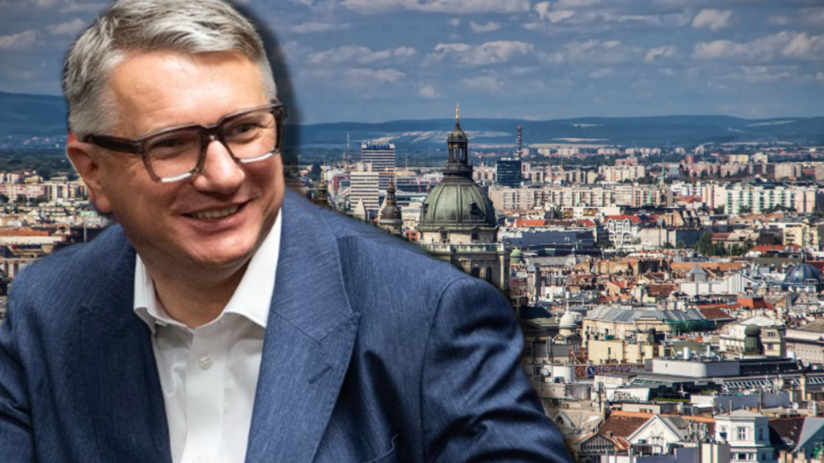 Uśmiechnięty mężczyzna w okularach i garniturze na tle panoramy miasta.