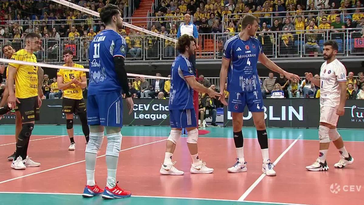 Siatkarze w niebieskich i białych strojach na boisku podczas meczu siatkówki.