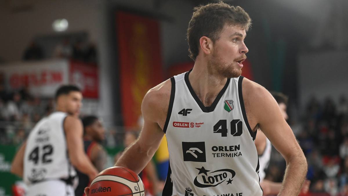 Koszykarz w białej koszulce z numerem 40, trzymający piłkę do koszykówki, podczas meczu.