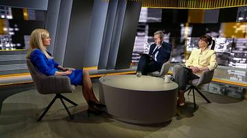 Trzy osoby siedzą w studiu telewizyjnym, dwie kobiety i jeden mężczyzna, podczas dyskusji.