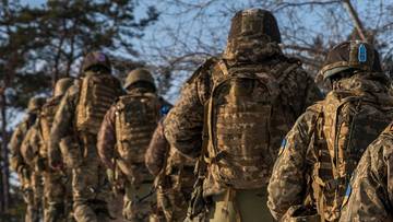 Grupa żołnierzy idąca w kolumnie po zaśnieżonym terenie.