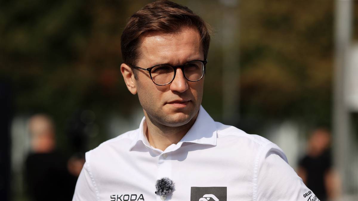 Mężczyzna w okularach i białej koszuli z logotypami Skoda i Orlen.