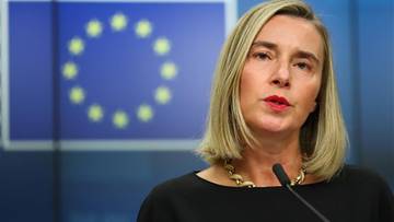 Federica Mogherini przemawia przed niebieskim tłem z flagą Unii Europejskiej.