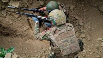 Dw&oacute;ch żołnierzy w kamizelkach taktycznych i hełmach celuje z broni.