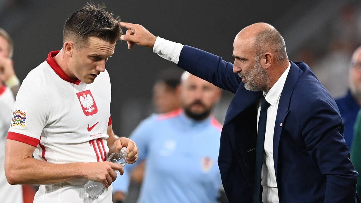 Trener Michał Probierz poprawia włosy piłkarzowi w białej koszulce reprezentacji Polski.