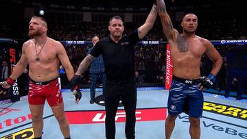 Dwóch zawodników MMA i sędzia po walce, jeden z zawodników wygrywa.