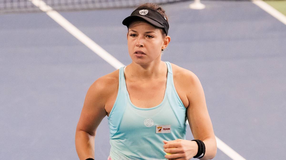 Polska tenisistka w niebieskim stroju sportowym i czapce z daszkiem na korcie tenisowym, zdeterminowana.