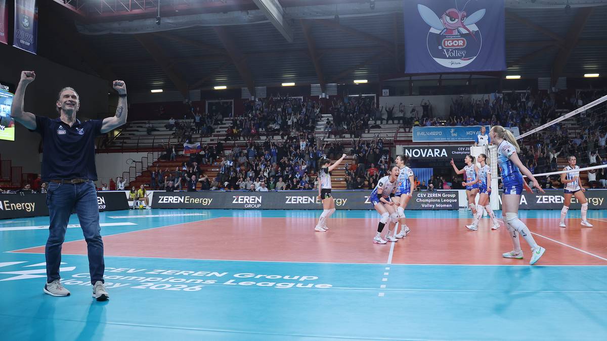 Trener z podniesionymi rękami świętuje zwycięstwo swojej drużyny siatkarskiej na boisku.