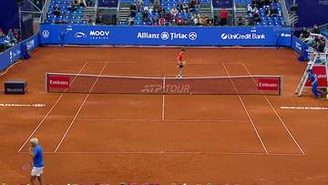 Dw&oacute;ch tenisist&oacute;w grających na korcie ziemnym podczas meczu ATP Tour. Jeden z nich jest bliżej kamery, a drugi stoi na środku kortu.