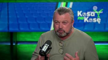 Mężczyzna z siwiejącymi włosami i zarostem, ubrany w bluzę, siedzi przed mikrofonem i gestykuluje.