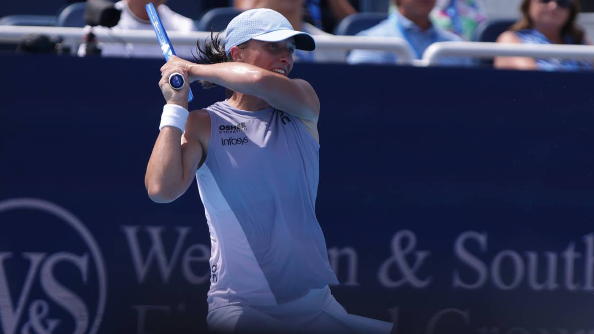 Tenisistka Iga Świątek w trakcie uderzenia piłki rakietą tenisową.