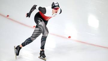 Panczenista w kombinezonie ślizga się po lodowisku.