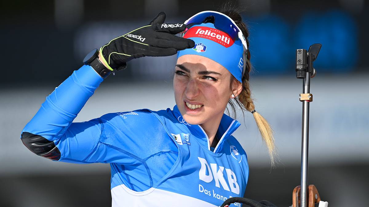 Biathlonistka w niebieskiej kurtce i czapce z daszkiem z logo "Felicetti" wykonuje salut.