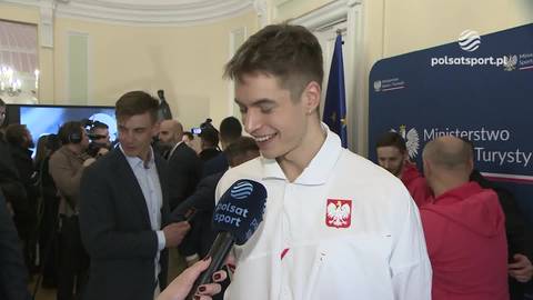 Młody mężczyzna, Włodzimierz Semirunnij, trzyma mikrofon i uśmiecha się, m&oacute;wiąc o dumie z niesienia polskiej flagi.