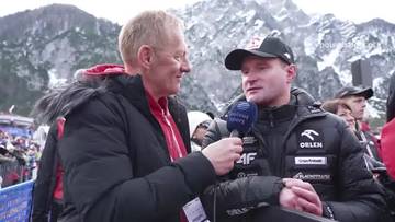 Maciej Maciusiak udziela wywiadu w zimowej scenerii, ubrany w odzież sportową z logo sponsora.