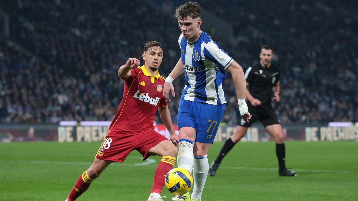 Dw&oacute;ch piłkarzy walczy o piłkę na boisku, jeden w czerwonej koszulce, drugi w niebiesko-białej.