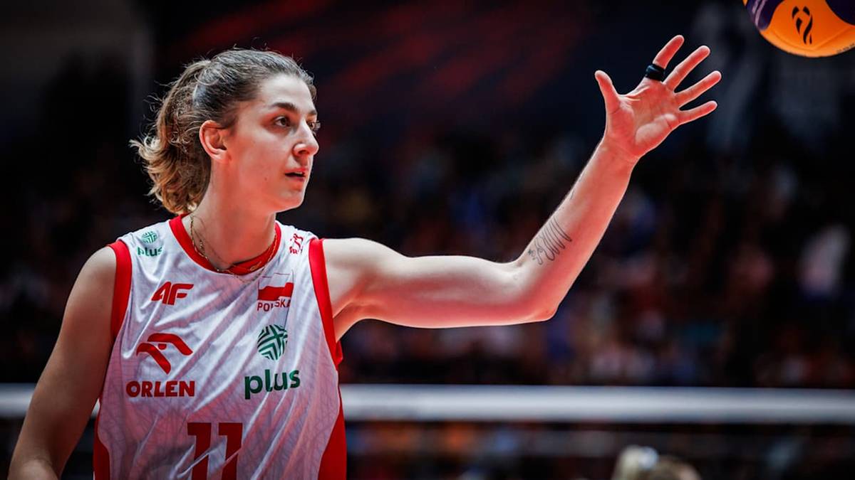 Siatkarka w białej koszulce z czerwonymi elementami i numerem 17, w trakcie meczu, podrzuca piłkę.