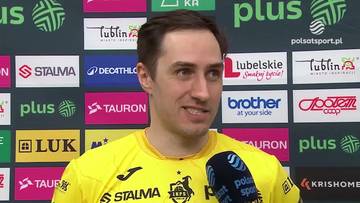 Mateusz Malinowski, sportowiec w ż&oacute;łtej koszulce, udziela wywiadu na tle kolorowej ściany z logotypami.