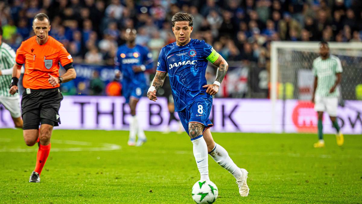 Piłkarz Enzo Fernandez w niebieskiej koszulce Chelsea prowadzi piłkę na boisku.