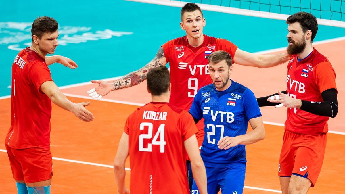 Pięciu siatkarzy w czerwonych i niebieskich strojach podczas meczu.