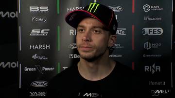 Marco Bezzecchi, zawodnik MotoGP, w czapce z daszkiem z logo Monster Energy, na tle ściany z logotypami sponsor&oacute;w.